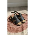 Handcrafted Leather Slingback Sandals in black with perforated texture on a woven rug.