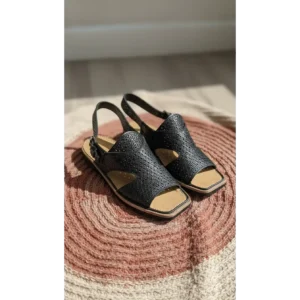 Handcrafted Leather Slingback Sandals in black with perforated texture on a woven rug.